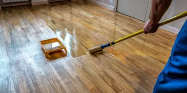 Wooden floor being cleaned with a mop and bucket.